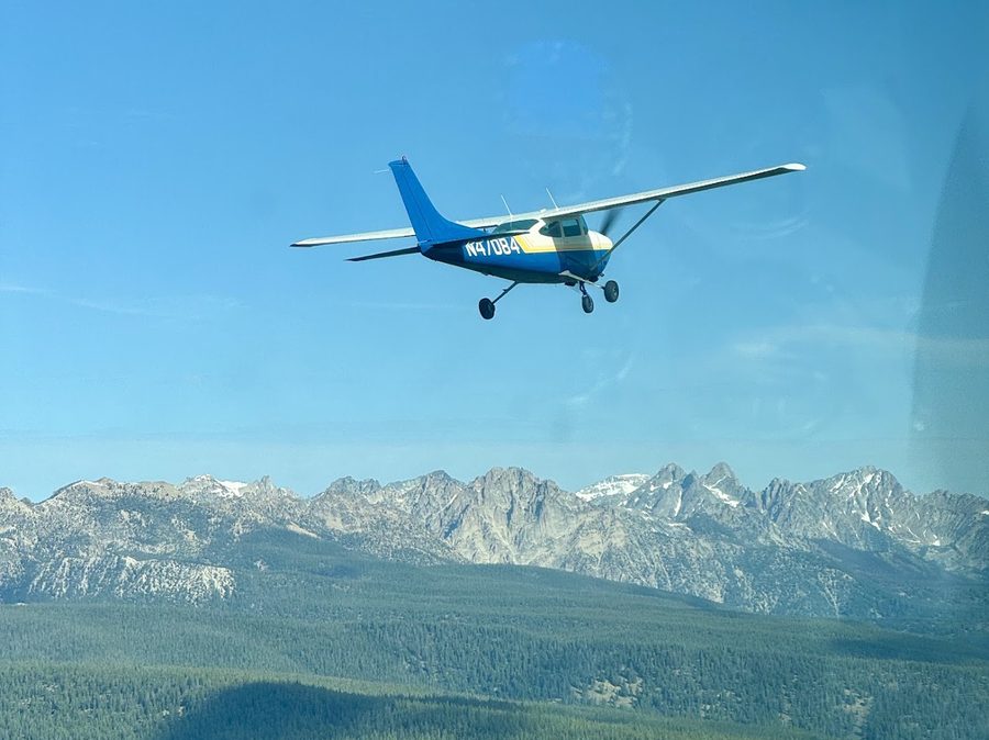 Two aircraft flying in loose formation over forested mountains